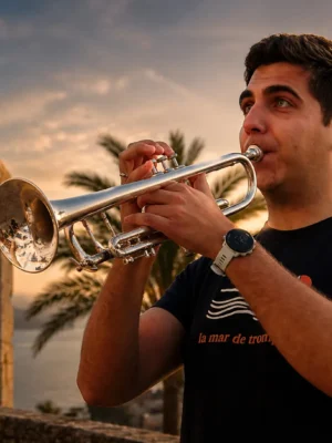 Antonio Torres tocando la trompeta junto a un castillo al atardecer